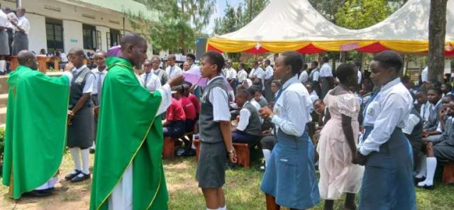 Rev Fr Deus Tweyongyere giving communion to students