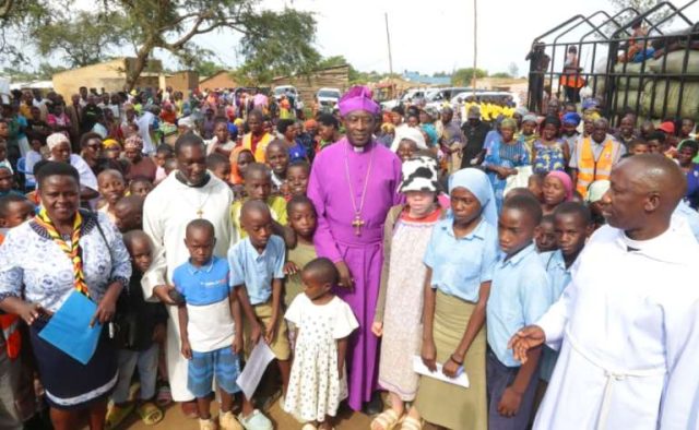 Archbishop Kaziimba Mugalu share a light moment with children in the Nakivale