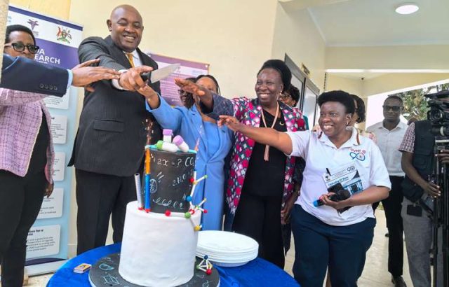 Hon Dr Chris Baryomunsi is joined by the Management and staff of Uganda Virus Research Institute to cut a cake in celebration of 90 years