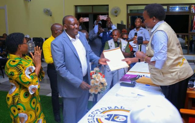 Ms Akau Eunice Christine hands over the results declaration form to the winner of Adjumani West by-election James Leku Pilli